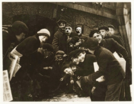 A gathering of children rolling die in an alley.